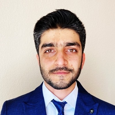 Professional headshot of Mujtaba Ahmadi. Ahmadi has dark hair, is wearing a blue suit with a tie, and is looking directly into the camera.